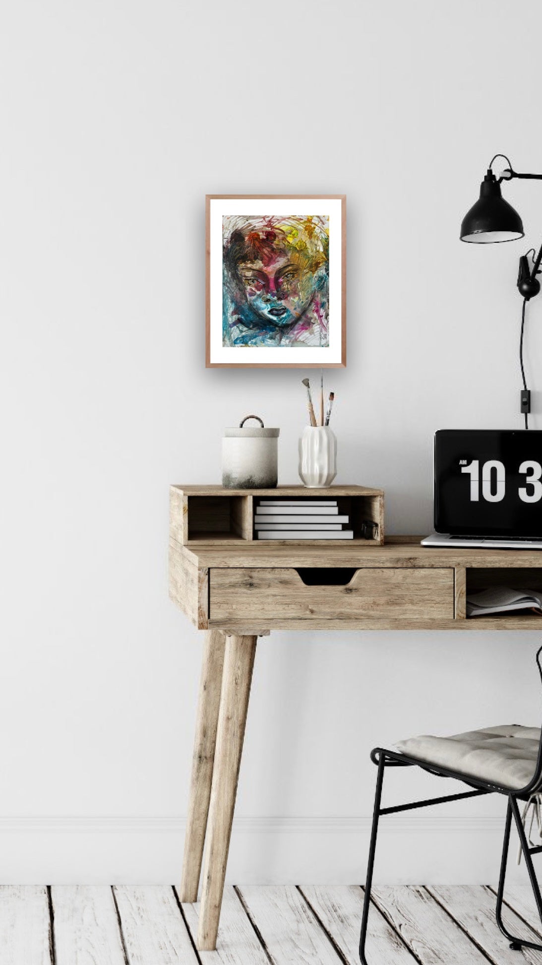 Wooden desk with a chair, framed artwork, and decorative items against a white wall.