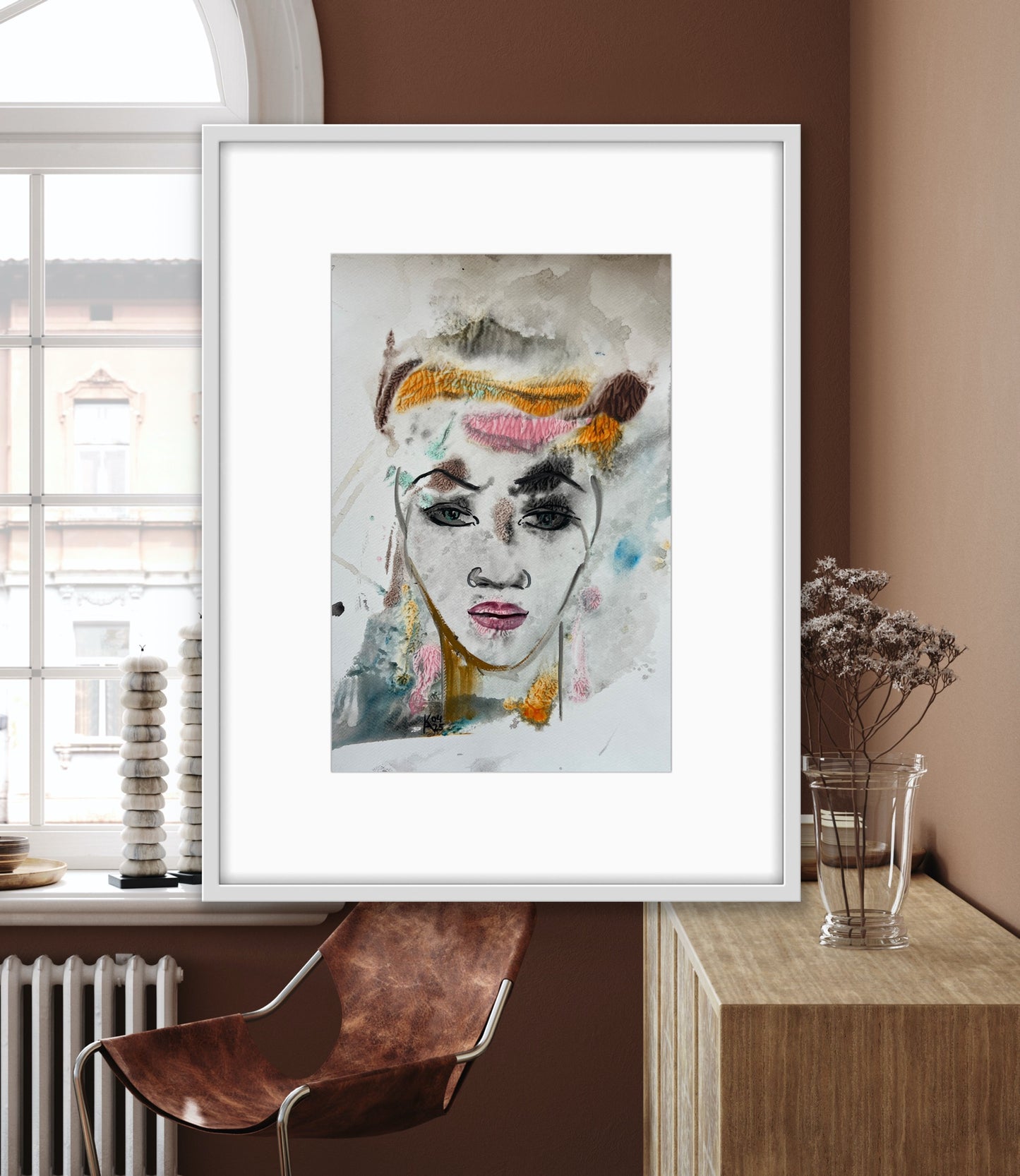 Framed abstract art print of a woman's face on a wall in a modern interior setting.