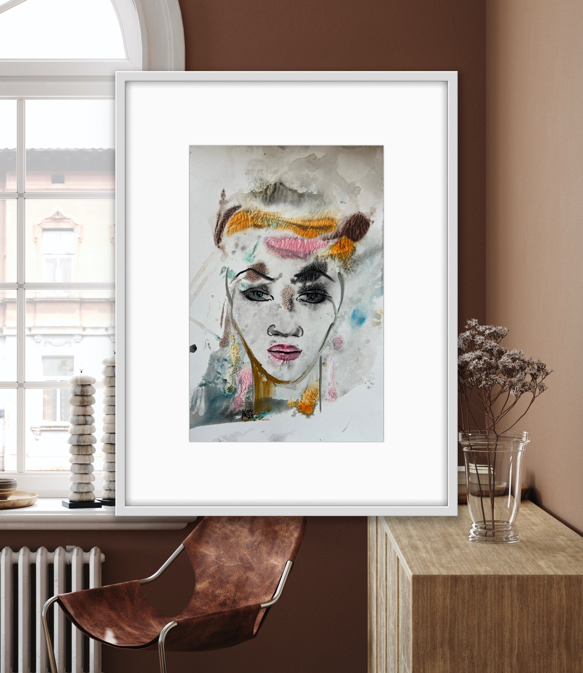 Framed abstract art print of a woman's face on a wall in a modern interior setting.