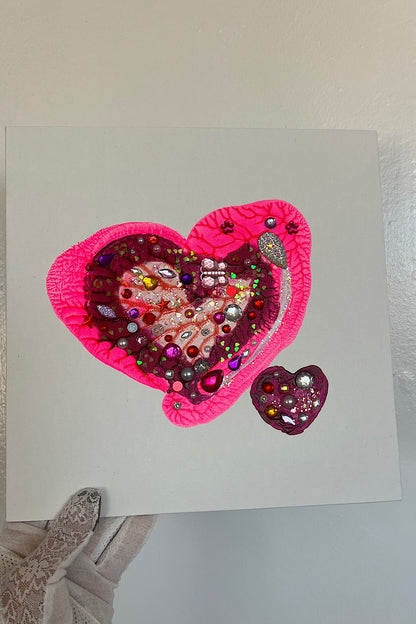 Heart-shaped card with rhinestone embellishments held by a gloved hand.