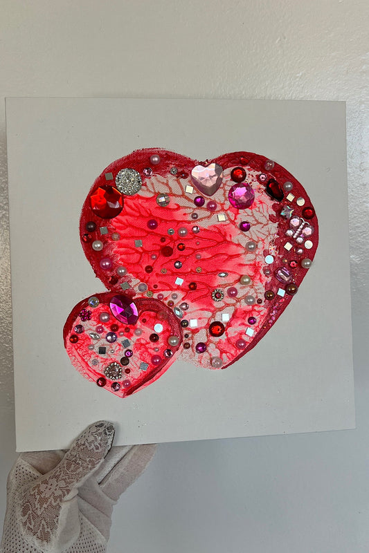 Decorative heart-shaped card with sequins and beads on a plain background