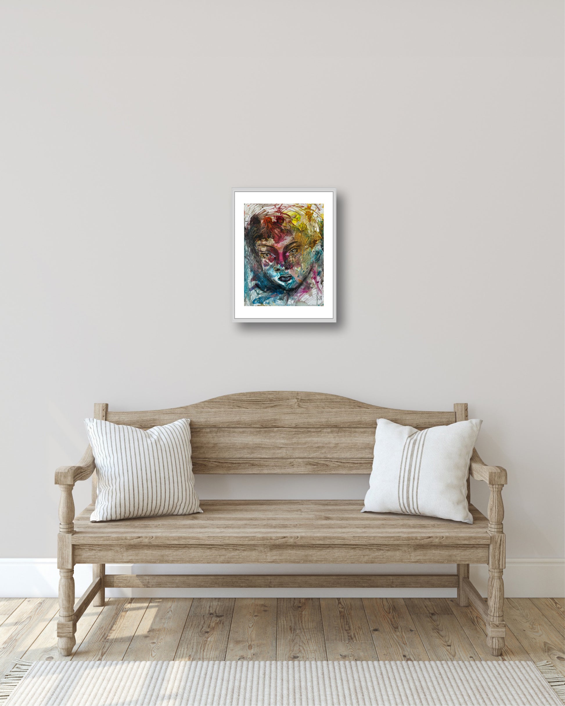 Wooden bench with white pillows in a room with a colorful abstract painting on the wall.