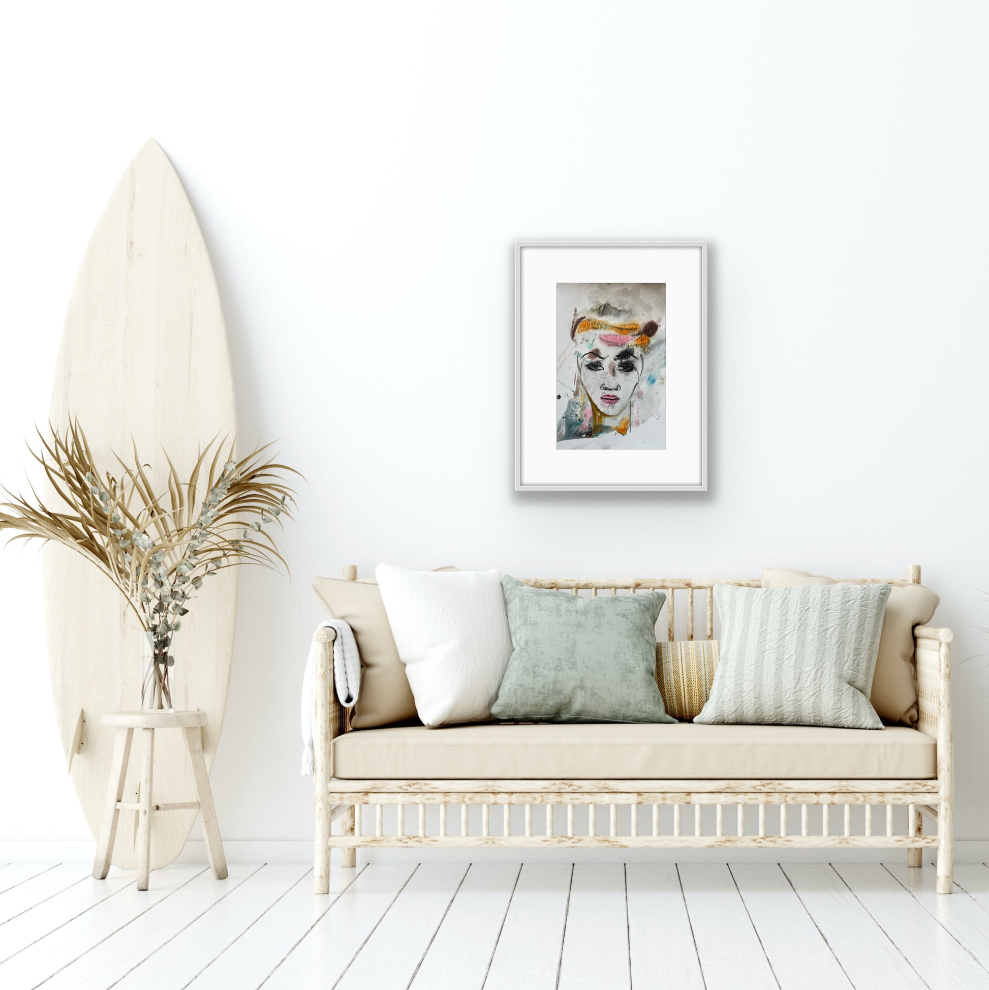Living room with a white sofa, surfboard, and framed artwork on a white wall.