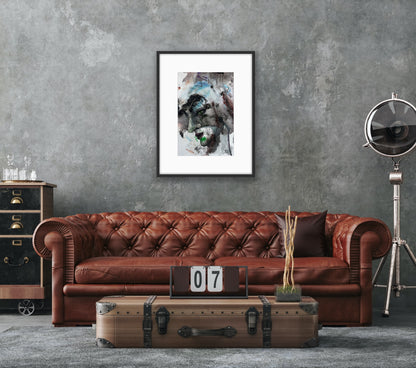 Brown leather sofa in a room with a textured gray wall, framed abstract art, and vintage suitcase.