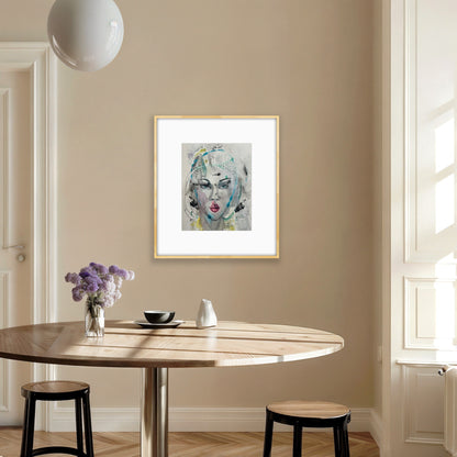 Watercolor art print in a gold frame displayed in a minimalist kitchen dining area with a light wood table, white pendant lamp, and purple flower arrangement