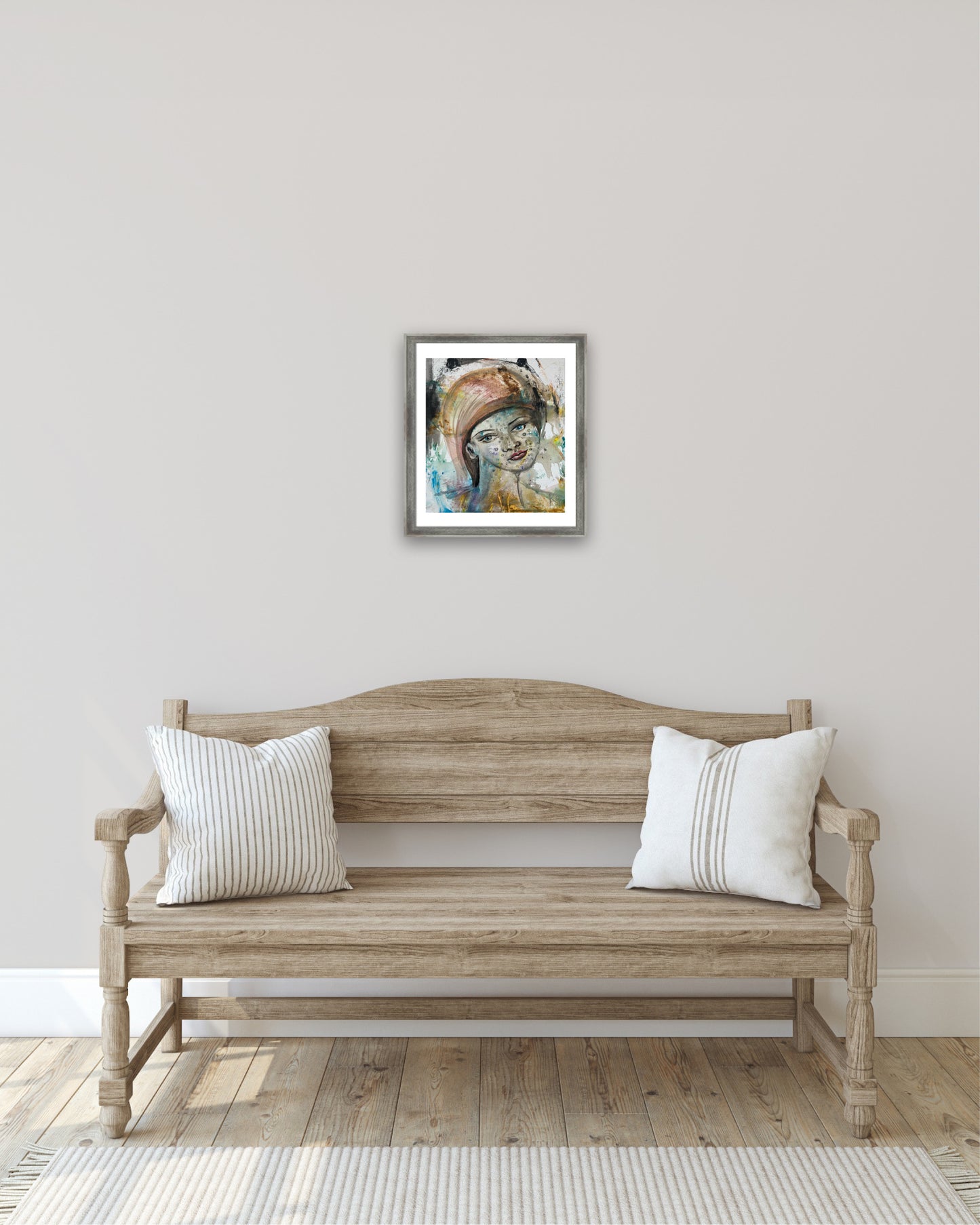 Original acrylic portrait painting framed above wooden bench in light neutral entryway, expressive female portrait wall art