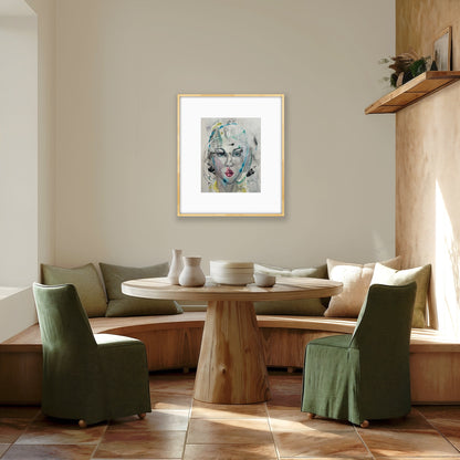 Framed female face painting hanging in a cozy dining nook with a round wooden table, sage green chairs, and soft natural sunlight