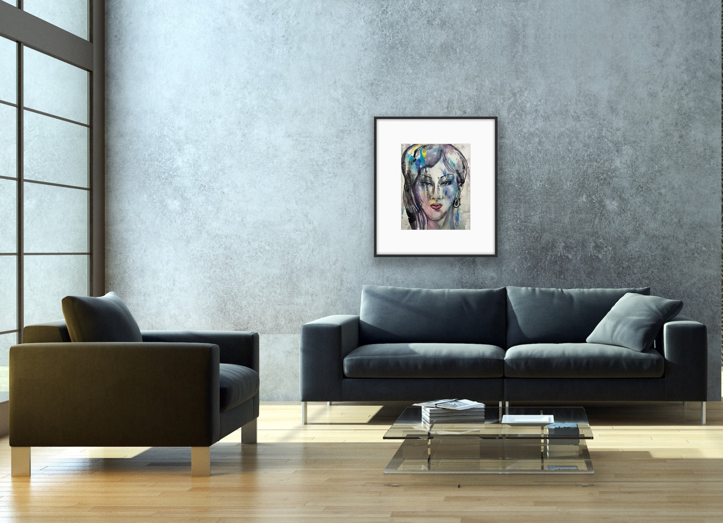 Framed watercolor abstract face art hanging on a textured grey concrete wall in a minimalist living room, positioned above a dark charcoal sofa and a glass coffee table with books and natural sunlight