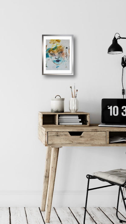 Original acrylic portrait painting Silence framed in silver, displayed above a wooden desk in a modern home office interior