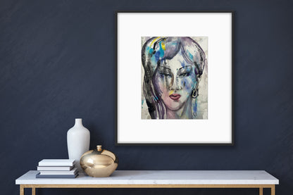 Framed watercolor portrait art hanging on a dark navy blue wall above a white marble console table, styled with a white vase, gold decorative sphere, and books for modern home gallery wall decor