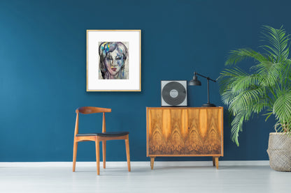 Framed watercolor portrait artwork displayed on a deep teal blue wall above a wooden mid-century cabinet, styled with a vinyl record player, black lamp, and a potted palm plant for an elegant retro decor setup